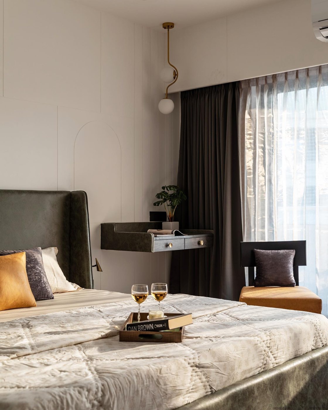 Bedroom with olive leather headboard, floating nightstand, arched wall panelling, and dark curtains by window.