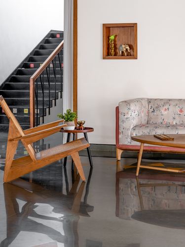 Living room corner with cane armchair, floral sofa, and staircase with patterned risers