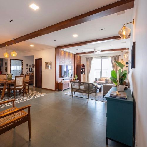 Open living-dining space with cane furniture, wood beams, exposed brick and patterned tiled runner