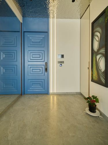 Entryway with paneled blue door, marble-look floor, and framed painting on white wall