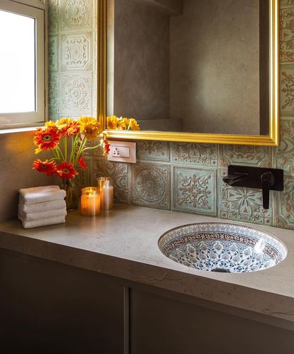 Bathroom vanity with patterned tile backsplash, gold mirror, and hand-painted ceramic sink