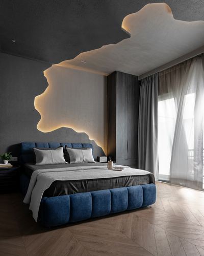Dark bedroom with blue tufted bed and glowing amoeba-shaped ceiling cove above headboard wall