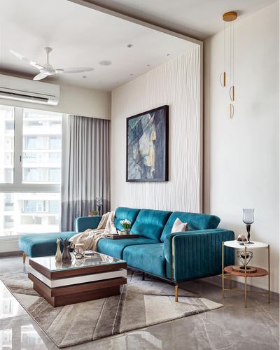 Living room with teal velvet sectional, fluted wall panel, layered coffee table and city view window
