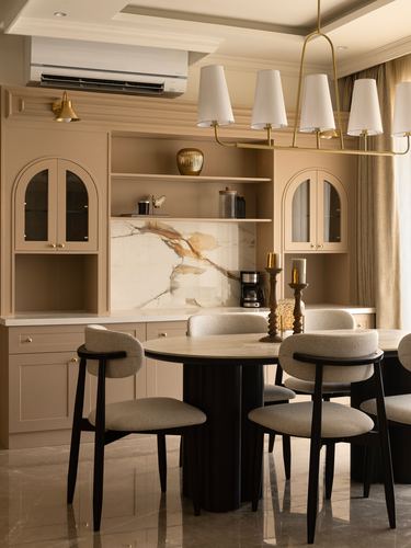 Beige dining room with round table, black chairs, arched cabinets and brass chandelier