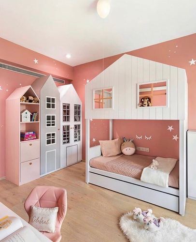 Child's bedroom with pink walls, star decals, and a white house-shaped bunk bed with trundle
