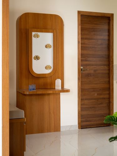 Wooden foyer console with frosted lotus-motif mirror beside a wood-paneled door