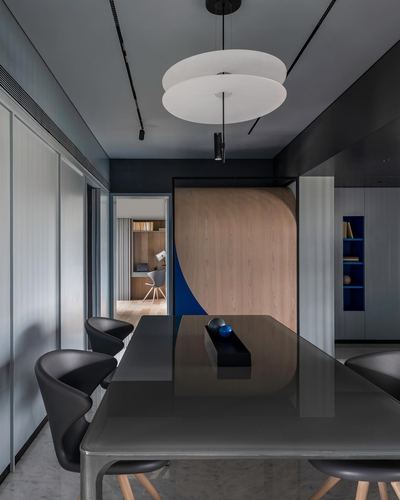 Dark dining room with glossy black table facing a curved wood and blue partition wall