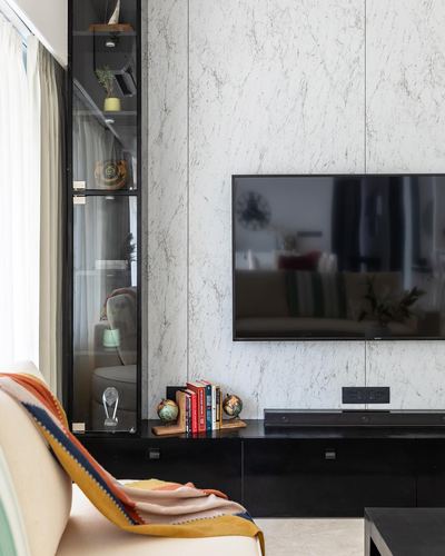 Living room with marble-panel TV wall, black cabinetry, glass display shelf, and striped cushions on sofa
