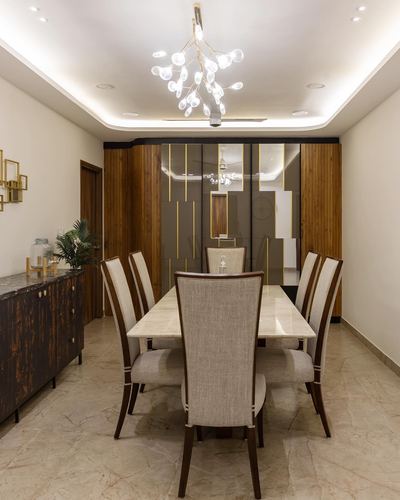 Dining room with marble table, cane-backed beige chairs, and mirrored gold-lined wall panels