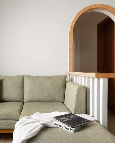 Sage green sofa beside arched wood-framed opening with fluted panel wall