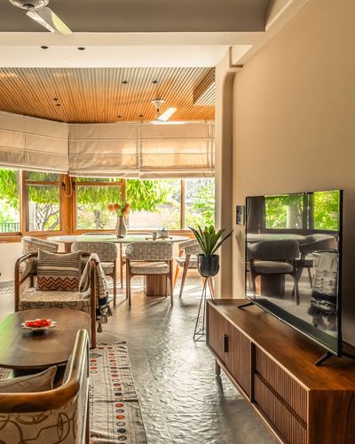 Living and dining space with wood-panelled ceiling, reeded console, and garden view through large windows