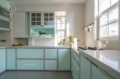 Pastel mint kitchen with white countertops, glass cabinets, and patterned floor tile near a bright window