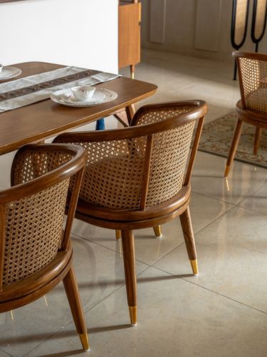 Close view of cane-backed wooden dining chairs around a table set with tea cups, stone floor beneath.