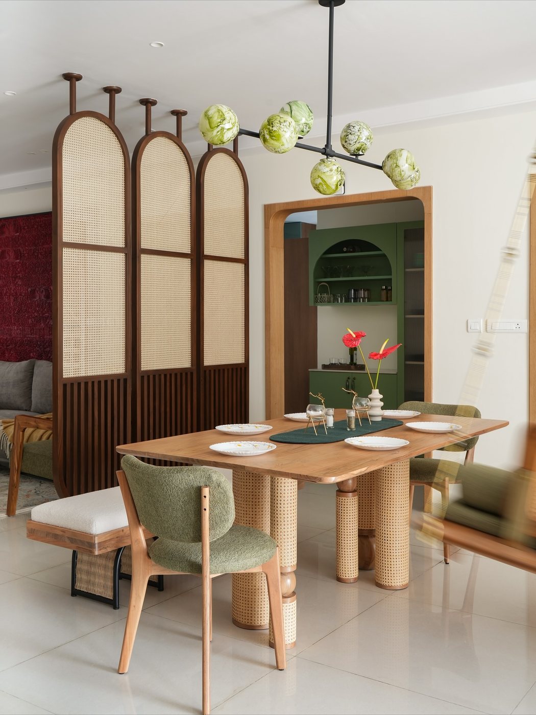 Dining room with cane screen, arched doorway to green pantry, green glass pendant lights over wooden table