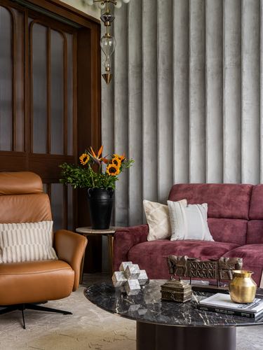Living room corner with tan recliner, maroon sofa, marble coffee table, fluted grey wall