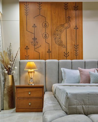 Bedroom with carved wooden peacock motif panel above grey channel-tufted headboard and wood bedside table