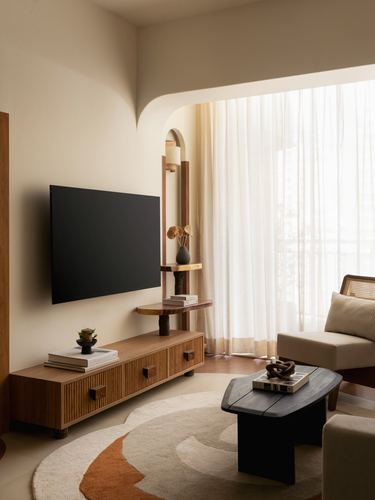 Living room with fluted wood tv console, arched shelf niche, and terracotta patterned rug near sheer curtained window