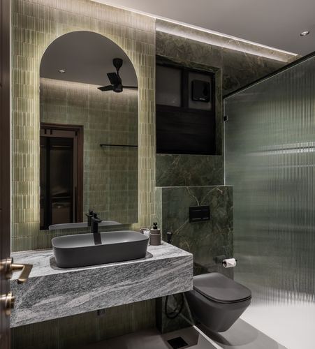 Green tiled bathroom with arched backlit mirror, stone vanity, and fluted glass shower partition