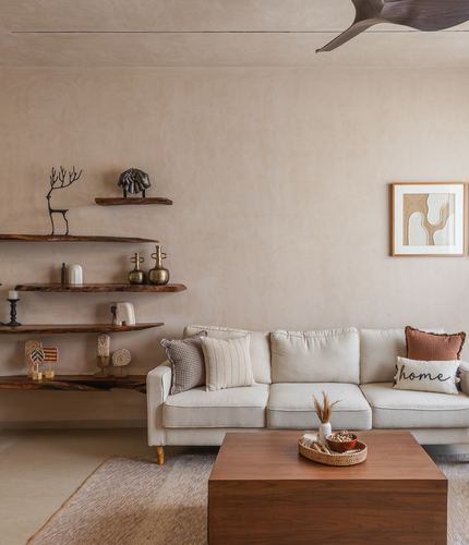 Beige living room with linen sofa, live-edge wood shelves, and framed art on textured wall
