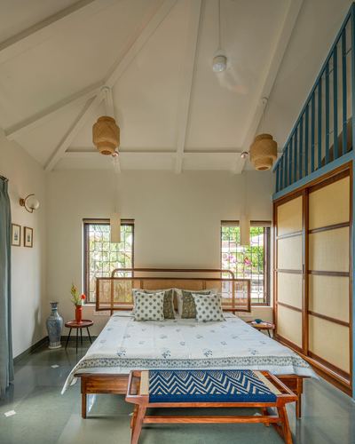 Bedroom with vaulted white truss ceiling, cane pendant lights, wooden bed and cane sliding doors