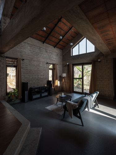 Double-height living room with textured stone walls, pitched clay-tiled roof and triangular window