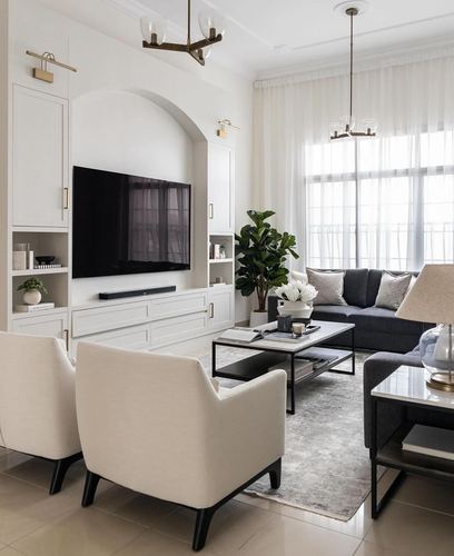 Living room with arched TV niche, white cabinetry, charcoal sofa, cream armchairs and marble coffee table