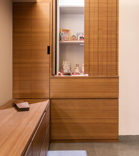 Wooden pooja unit with sliding shutters revealing deity idols in a Delhi apartment