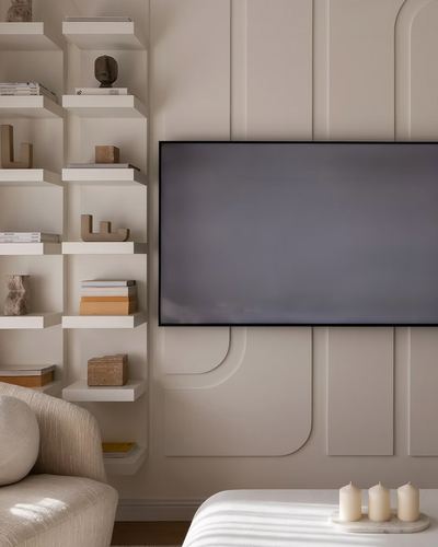Beige living room wall with fluted paneling, mounted TV, asymmetric shelves and sculptural decor