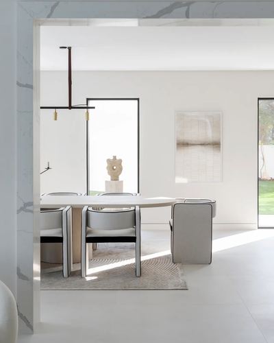 Minimalist dining room with oval table, grey chairs, and marble archway framing the view