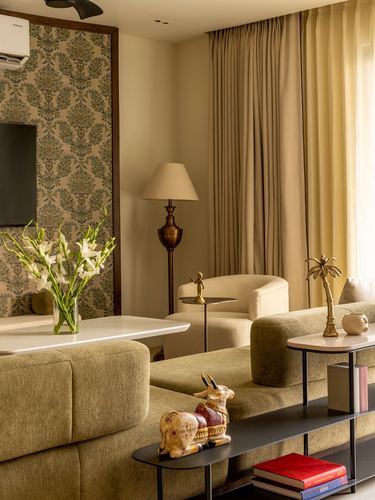 Living room with olive sofas, brass lamp, patterned wallpaper panel and gold curtains