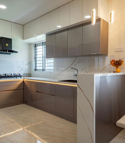 Modern kitchen with glossy grey cabinetry, veined stone counters, and warm pendant lighting