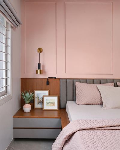 Pink-paneled bedroom with wood nightstand, brass sconce, and grey channel-tufted headboard