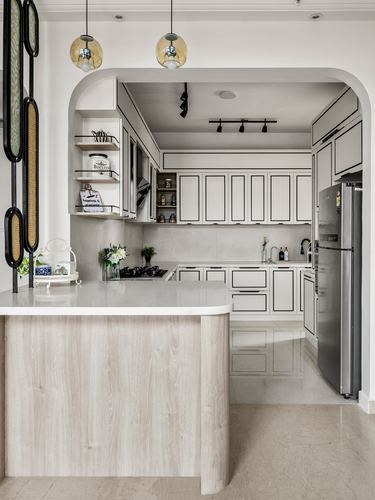 White kitchen framed by an arch, with a wood-clad island counter in foreground