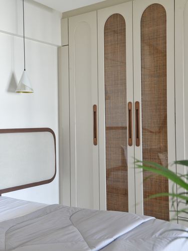 Bedroom corner with arched cane wardrobe doors, wooden headboard, and cone pendant light