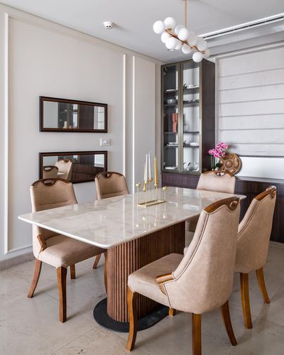 Dining room with marble table, fluted wood base, beige upholstered chairs, and glass display cabinet