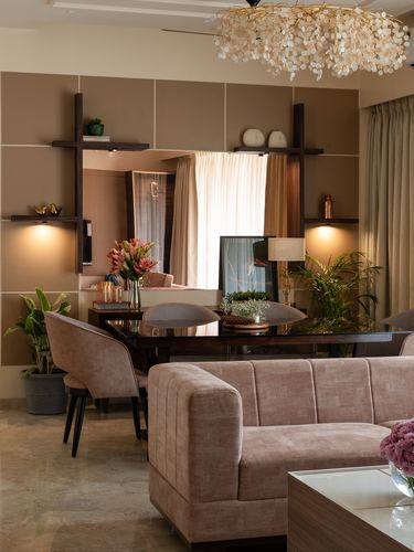 Dining area with dark wood table, cane chairs, mirror backdrop, and blush sofa in foreground