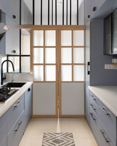 Galley kitchen with pastel blue cabinetry ending in a wood-framed frosted glass double door