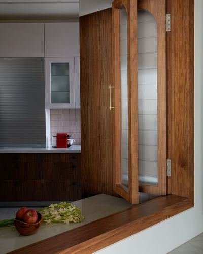 Wooden folding door with glass panels opens to a kitchen, fruit bowl on stone sill