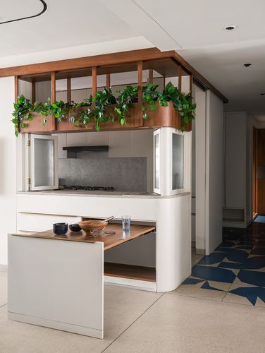 Curved white kitchen island with wood slat planter overhead and pull-out dining table