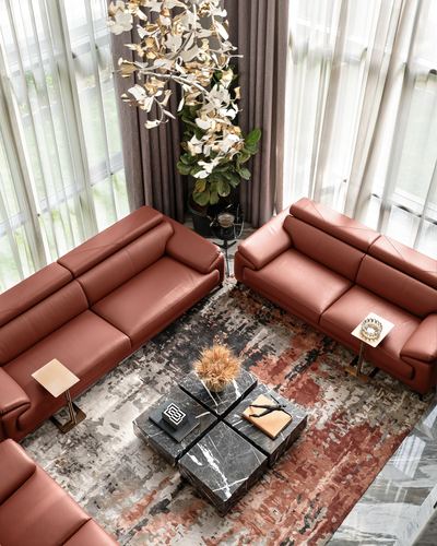 Top-down view of rust leather sofas around a black marble cube coffee table on a patterned rug