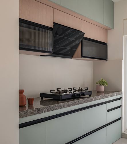 Kitchen counter with black gas hob, angular chimney hood, and sage green cabinetry