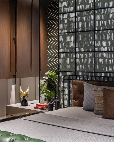 Bedroom corner with brown tufted leather headboard against a patterned dark green wall panel and wood-clad wardrobe