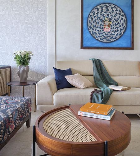 Living room with beige sofa, patterned artwork, and cane-topped round wooden coffee table