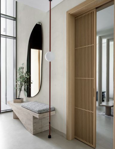 Entryway with oval mirror over travertine bench beside a slatted oak sliding door