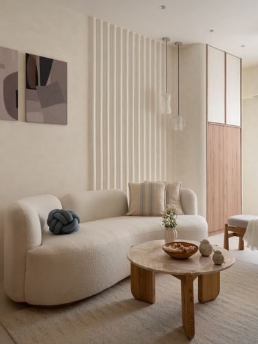 Cream boucle sofa against fluted plaster wall with round stone-top coffee table