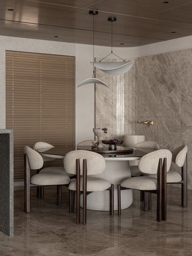 Round dining table with curved boucle chairs beneath sculptural pendant lights against a veined stone wall