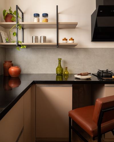 Kitchen corner with black countertop, terracotta pots, wood shelves and orange leather chair