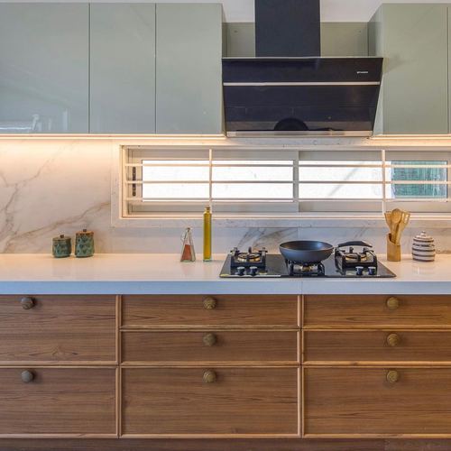 Kitchen counter with hob and chimney hood, marble backsplash, wooden drawers below