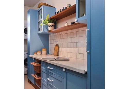 Blue kitchen cabinetry with wood floating shelves and white subway tile backsplash