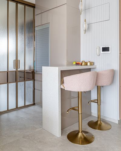 Terrazzo breakfast counter with two pink boucle gold-based bar stools against fluted glass panel